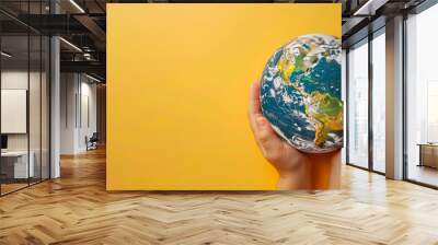 Children's hands hold the globe. Yellow background. Free space for text. Wall mural